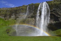Seljalandsfoss Wasserfall in Sommer mit einem Regenbogen und gr�nen Gras